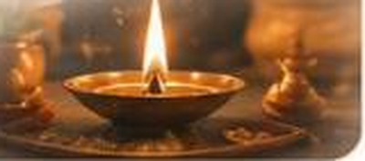 A lit oil lamp beside marigold flowers for an ancestor ritual