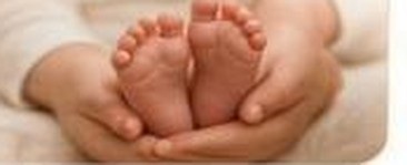 A parent gently holding their newborn's feet